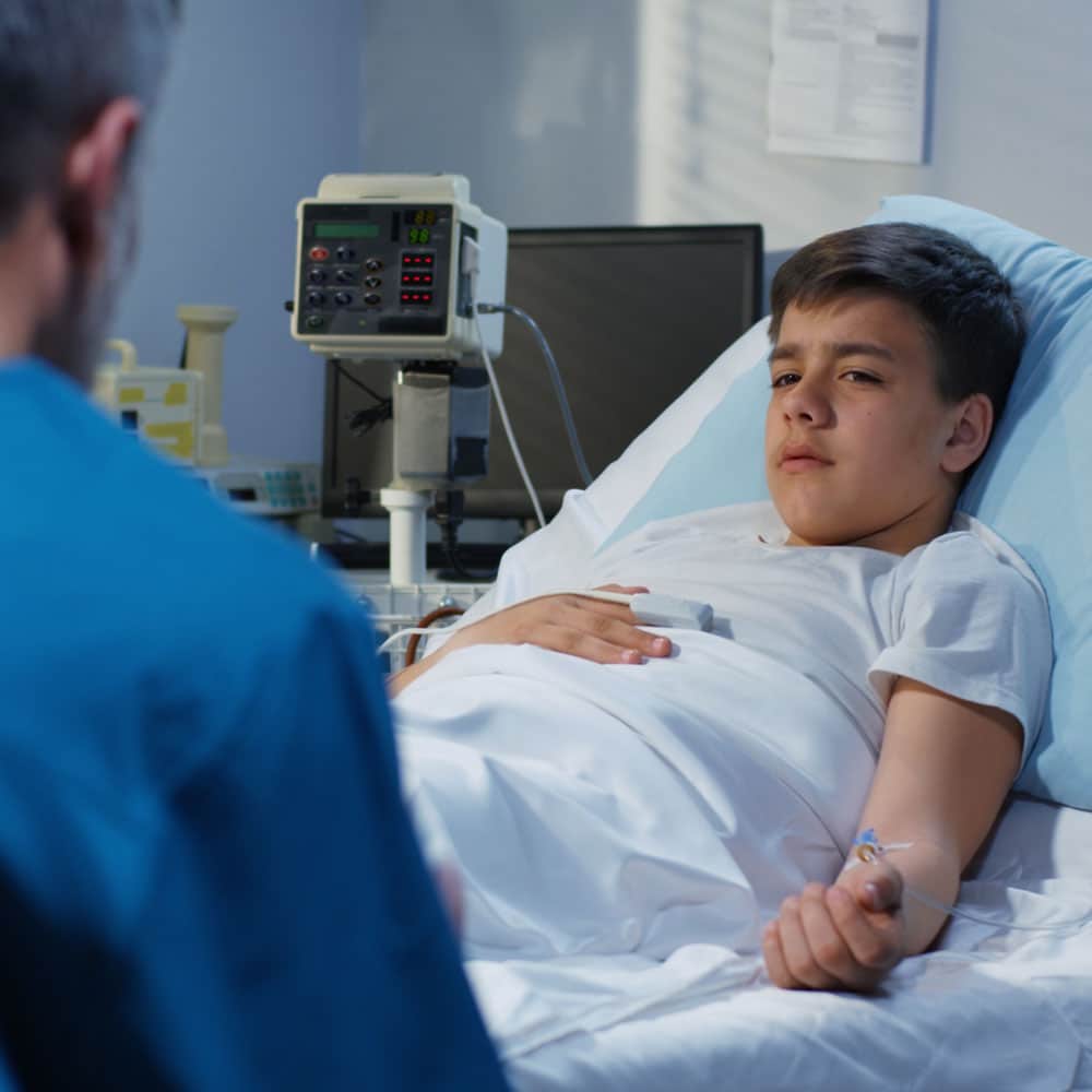 teenage boy in hospital bed talking to doctor