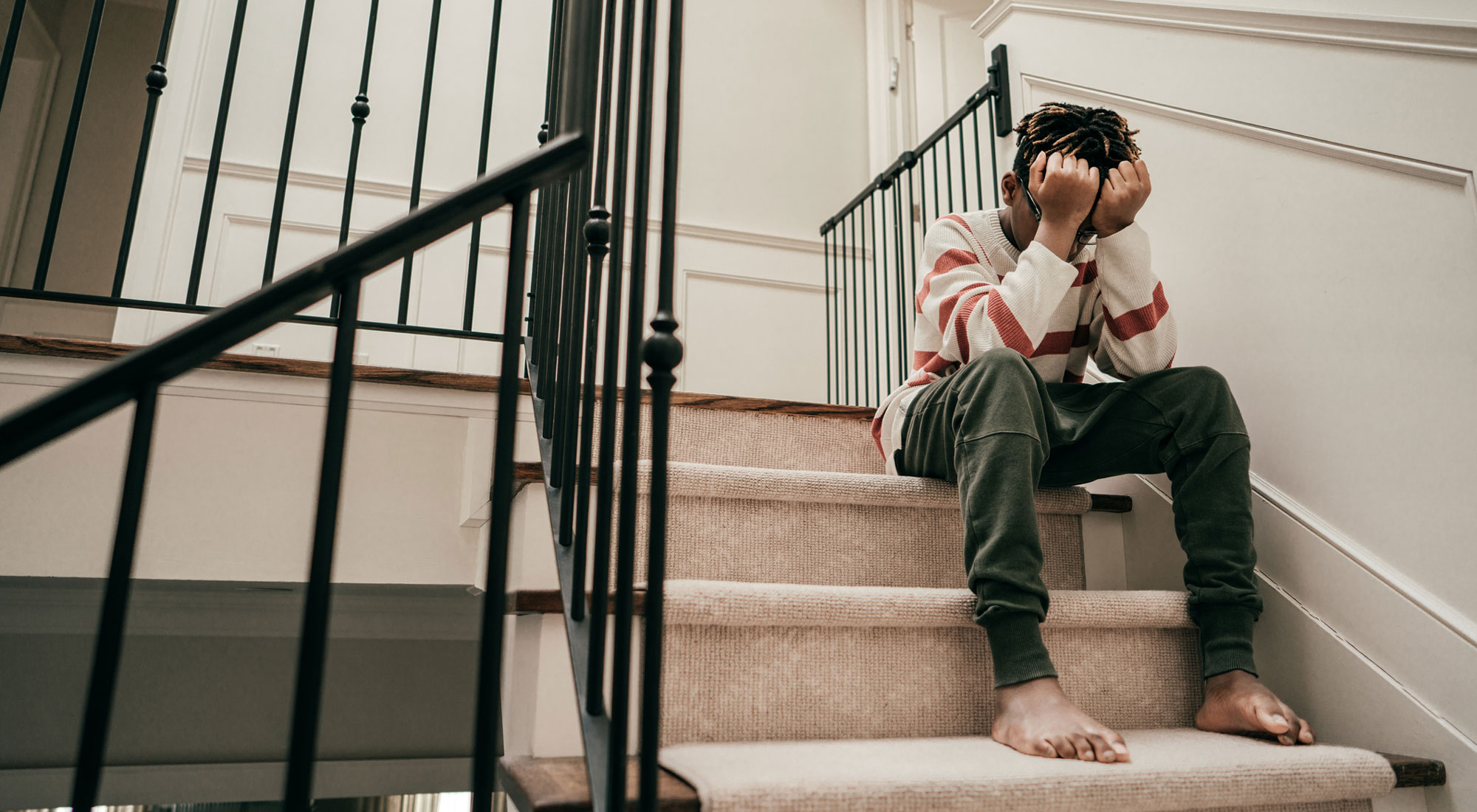 adolescent boy experiencing anxiety on stairs with head in hands